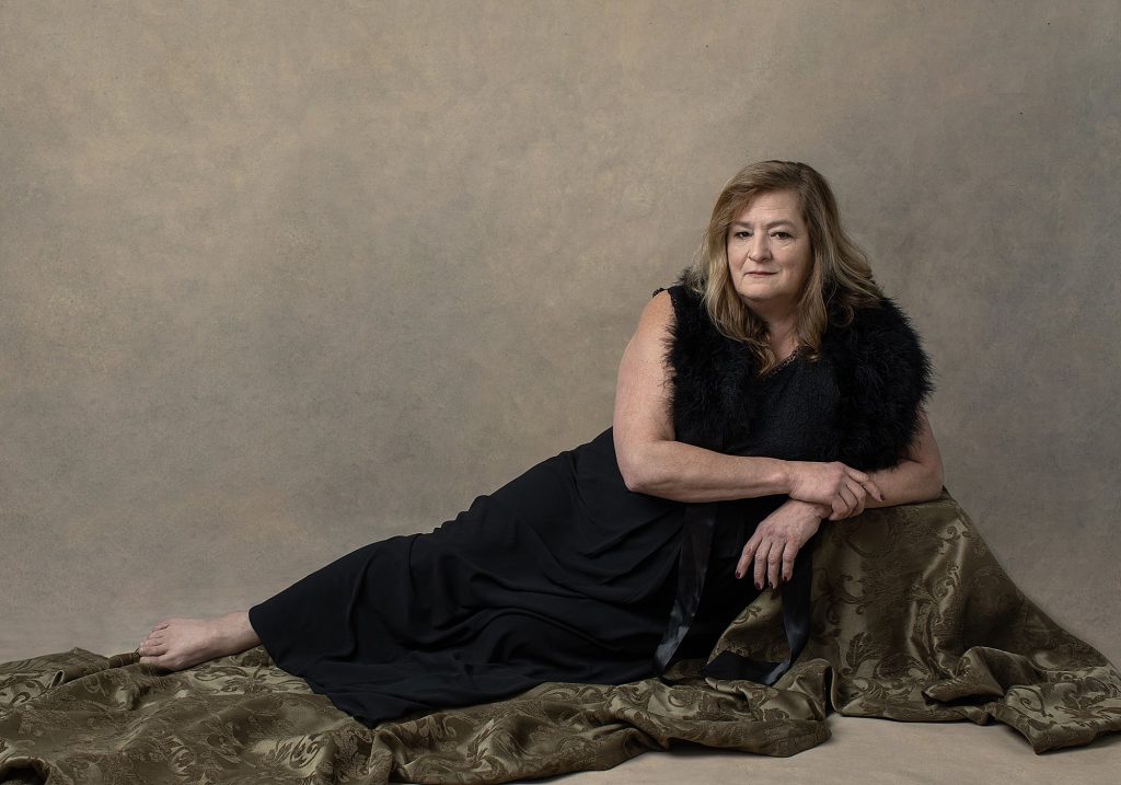 Portrait of Robin wearing a black dress, reclining, as part of her photo session for Extraordinary: the Over 50 Revolution