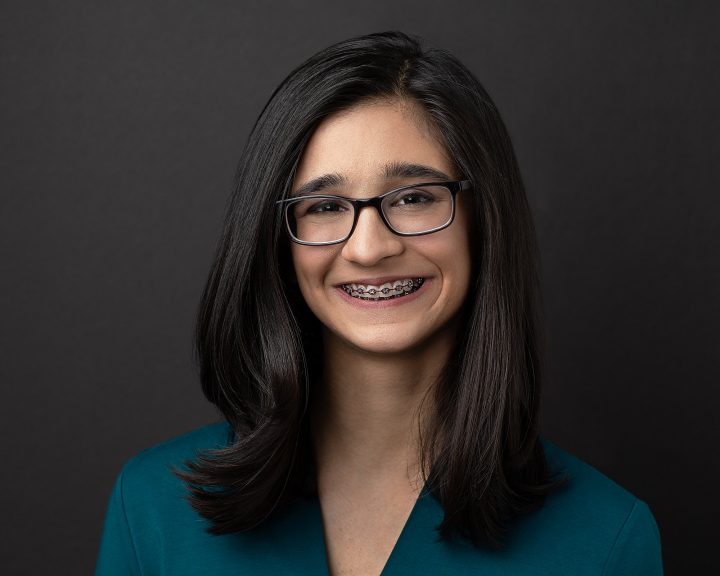 Riyah Patel headshot smiling braces in front of black background