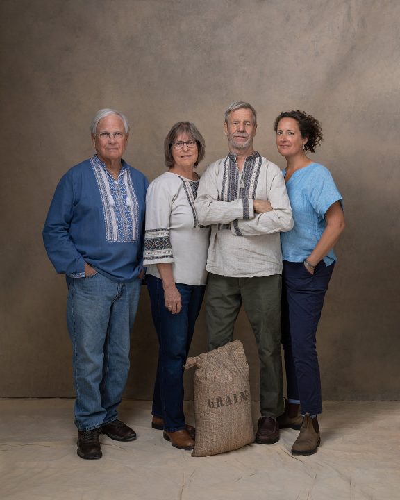 ©Maundy Mitchell - Steve Rand, Susan Mathison, Alex Ray, and Lisa Mure - Co-Founders, Common Man for Ukraine, wearing Ukrainian shirts, standing with a bag of grain