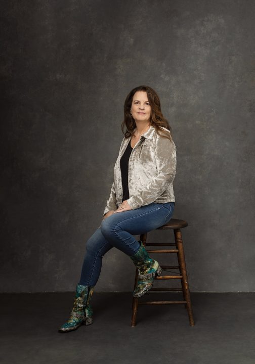 Heidi, seated on a stool, wearing boots, for Extraordinary: the Over 50 Revolution portrait experience