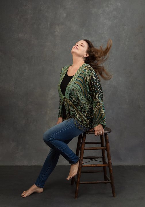 Portrait of Heidi sitting on a stool with wind-blown hair