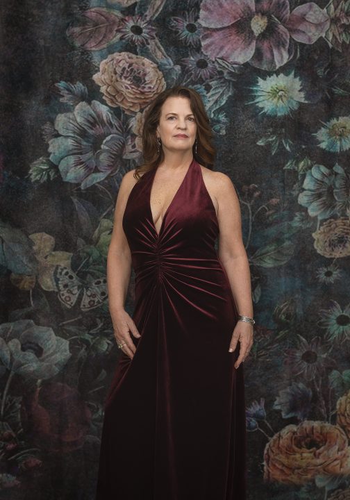 Heidi, wearing velvet gown in front of floral backdrop for her Extraordinary: the Over 50 Revolution portrait session