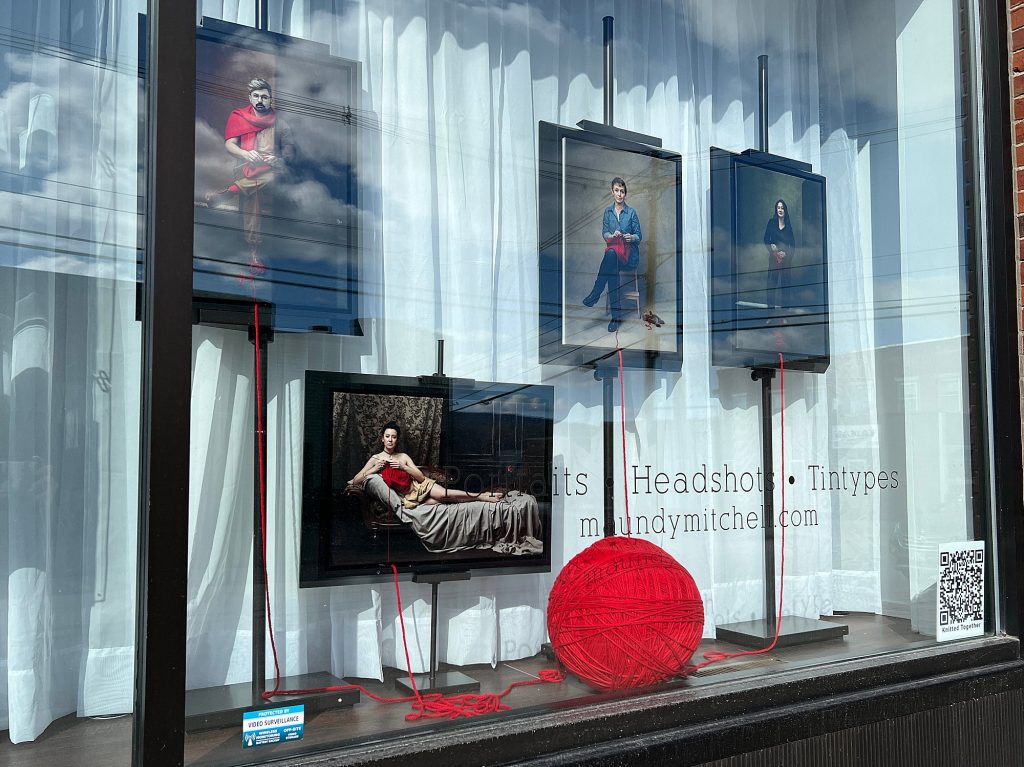 Studio window display from April 2023 with the first few portraits in the Knitted Together project
