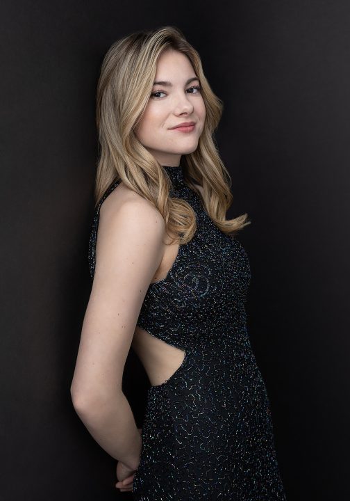 Senior photo of Brianna, wearing a sparkly gown with cutout sides, against a black background