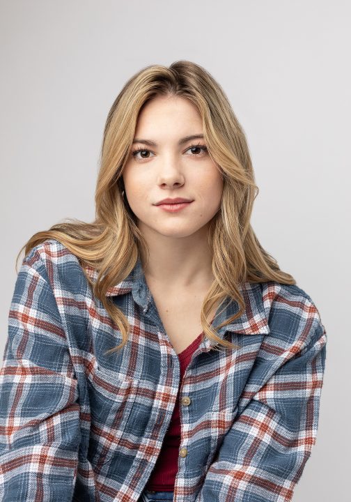 A casual high school senior photo of Brianna wearing a flannel shirt