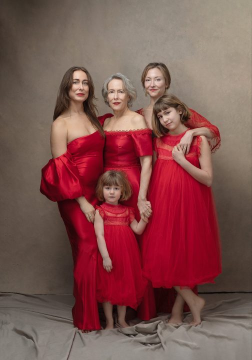 Portrait of three generations wearing red dresses