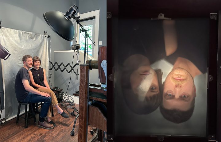 Rebecca and Jonathan posing for a tintype anniversary portrait and the upside-down camera view