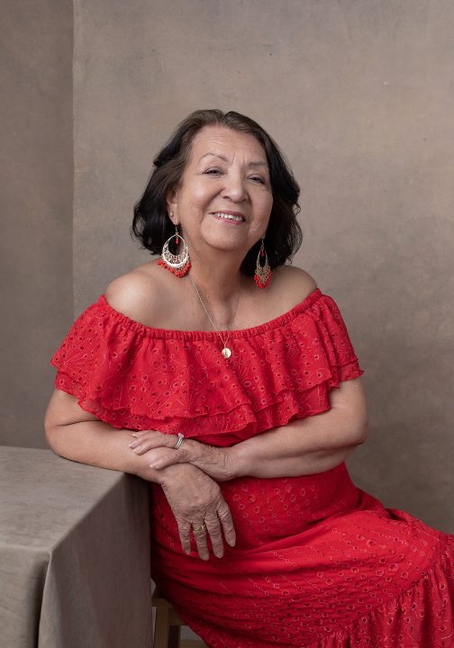Maria, wearing a red, off-shoulder dress for her Extraordinary: the Her 50 Revolution portrait session.