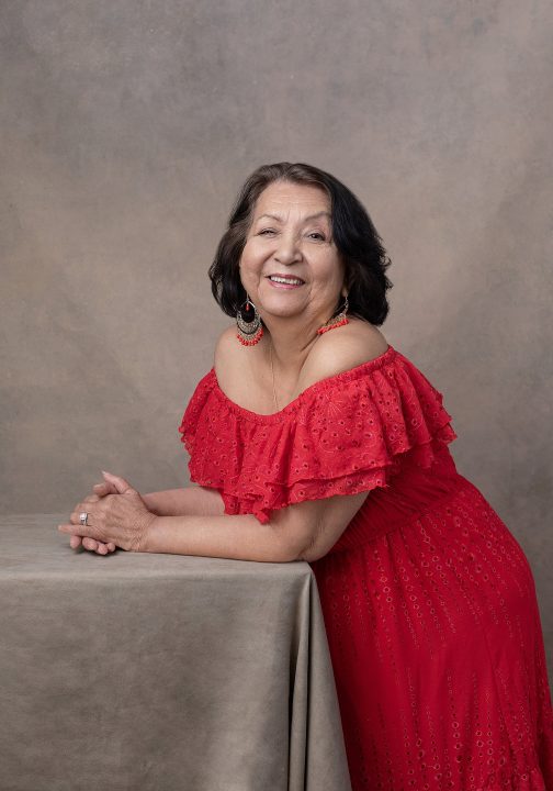 Maria, wearing a red, off-shoulder dress for her Extraordinary: the Her 50 Revolution portrait session.