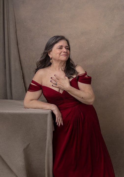 A portrait of Emilie wearing a red silk gown for her portrait session for Extraordinary: the Over 50 Revolution.