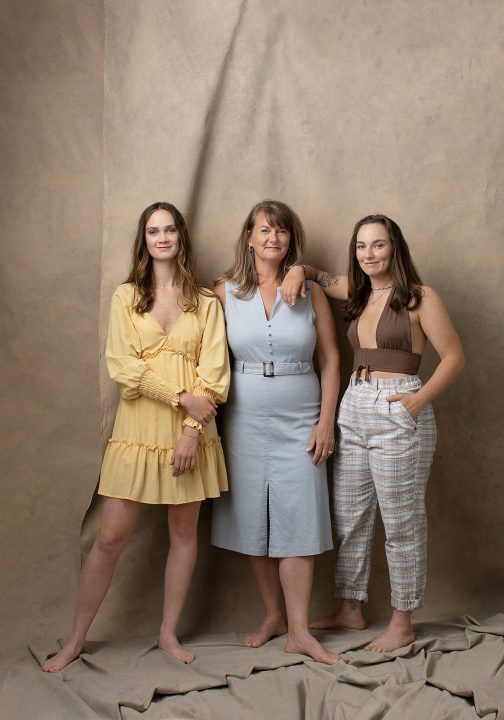 A casual studio portrait of a mother and two grown daughters