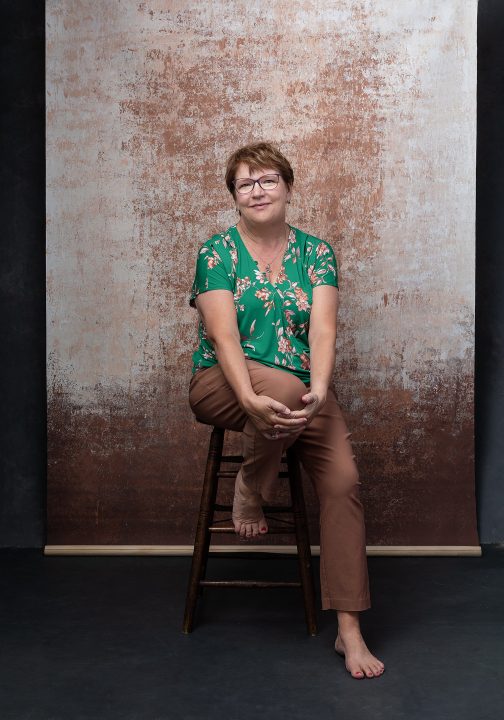 Casual portrait of Karen, seated in front of an abstract background