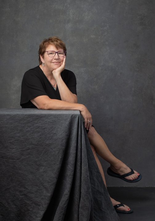 Portrait of Karen, seated, leaning at table