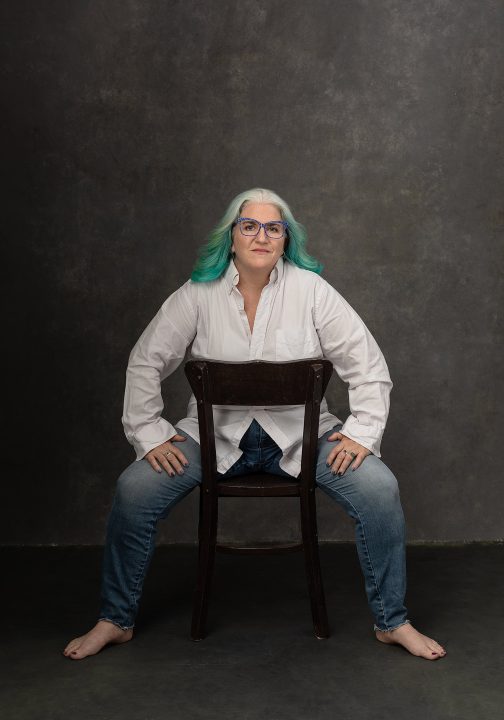 Portrait of Kim sitting backward in a chair during her photo session for the Over 50 Revolution