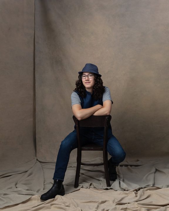 Portrait of David wearing a hat, sitting backward in a chair