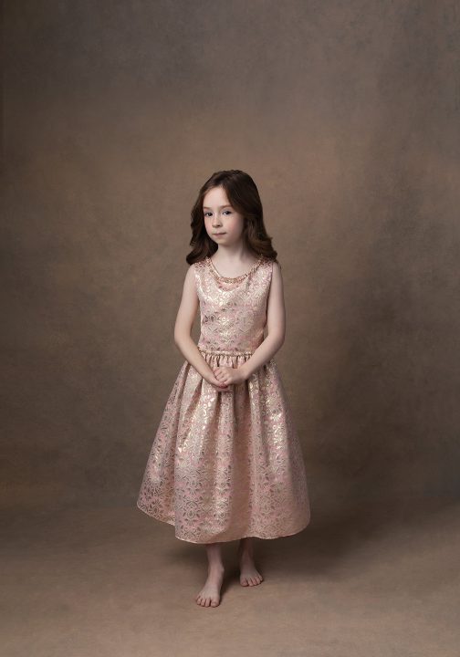 A photographic portrait in a painterly style, of a young girl wearing a gold and pink brocade dress