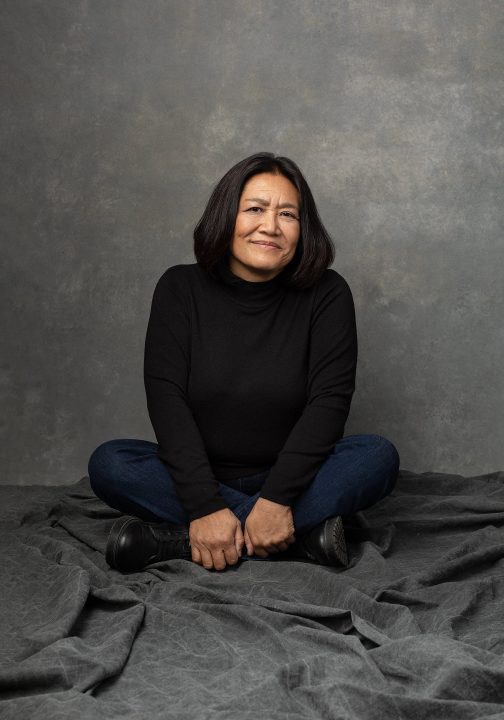 Portrait of Lisa, sitting cross-legged on the floor, wearing a black turtleneck