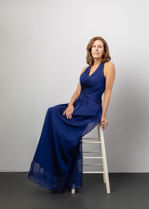 Robin, wearing a blue gown in front of a white backdrop during her session for The Over 50 Revolution