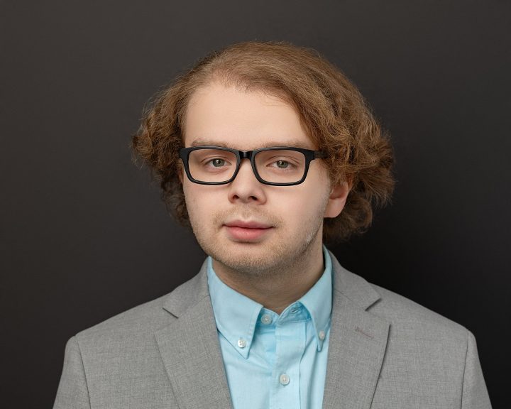 Professional headshot for new graduate from PSU, Michael. He is standing in front of a black background.