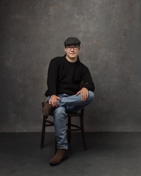 Portraits to celebrate 19 - David seated wearing Irish knit sweater and cap