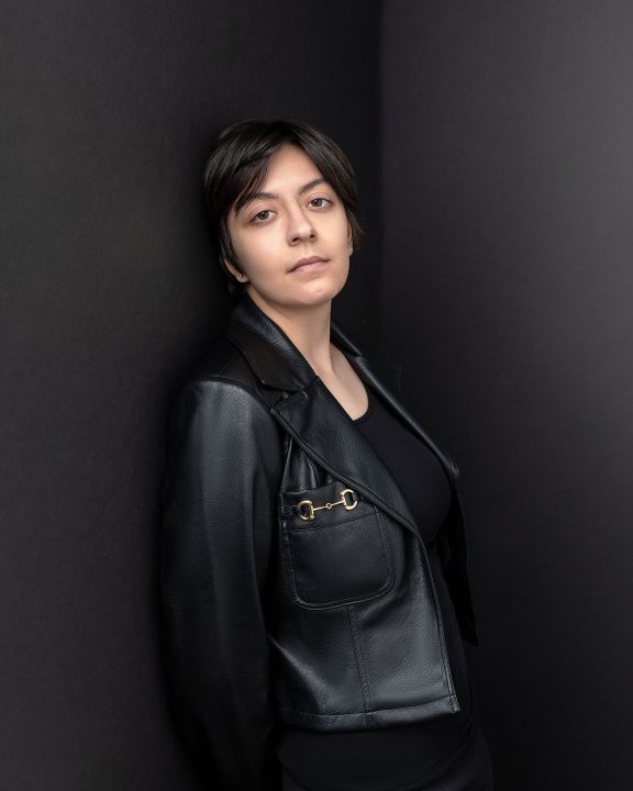 An acting headshot / portrait for Tori, a PSU student. She is leaning against a black wall